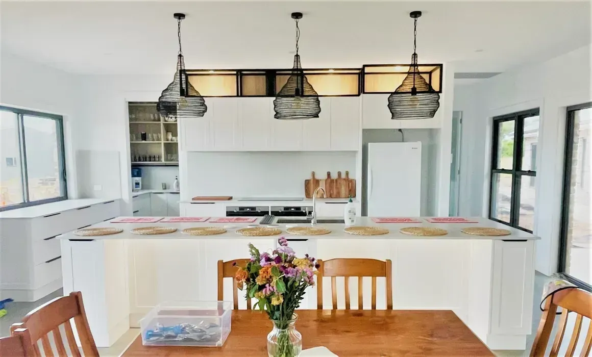 White kitchen renovation with large island and pendant lighting by Westside Kitchen Centre